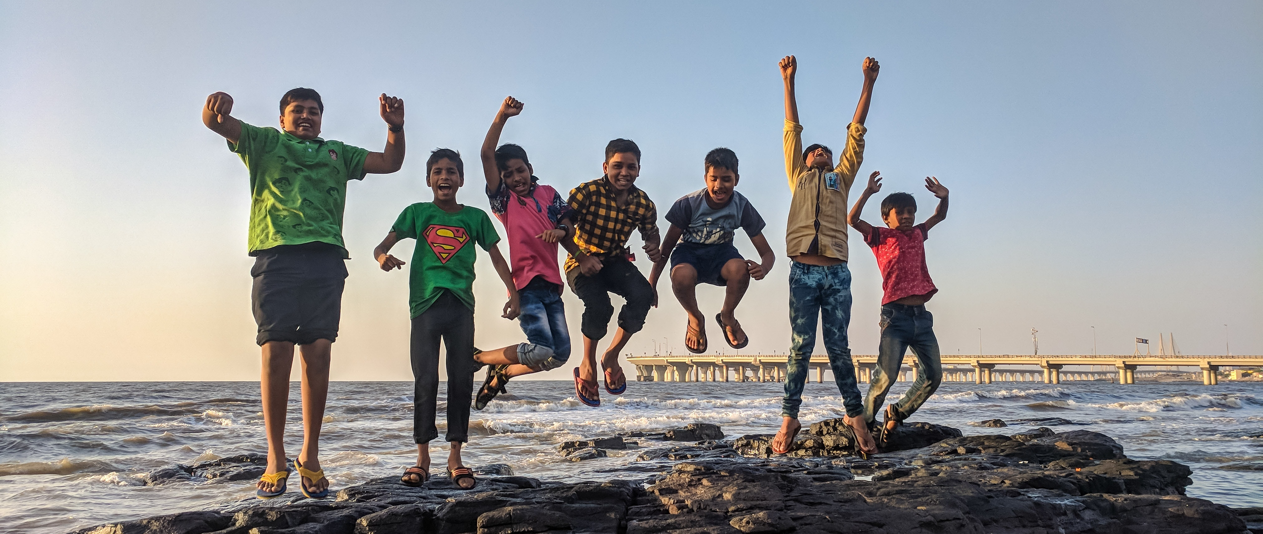 Group of children jumping and celebrating by the ocean